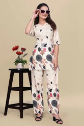 Woman wearing a floral outfit with sunglasses, standing next to a small table with a plant on a beige background