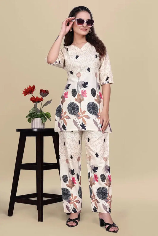 Woman wearing a floral outfit with sunglasses, standing next to a small table with a plant on a beige background