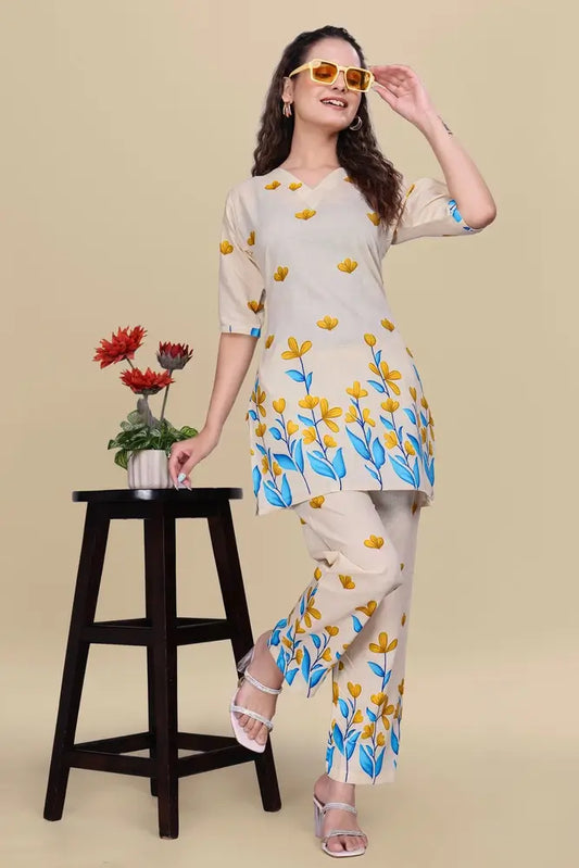 Woman wearing a floral outfit standing next to a stool with flowers on a beige background