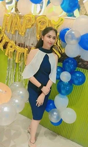 Woman posing in front of a 'Happy Birthday' sign with balloons