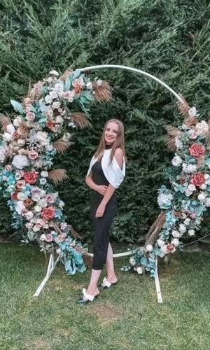Woman standing between two floral arches with a green background