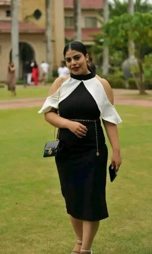 Woman in a black and white dress standing on grass with a blurred background