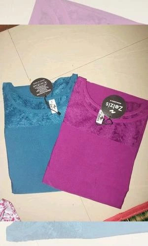 Two t-shirts, one blue and one purple, with size tags on a tiled floor.