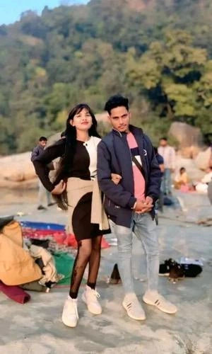 Two people standing on a rocky surface with a forest in the background