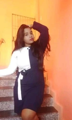 Woman in a black and white outfit sitting on steps with a warm-toned background