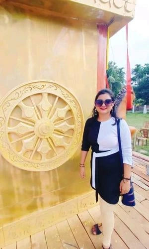 Woman standing in front of a large golden emblem on a wall