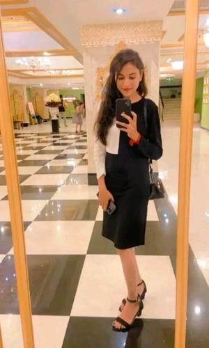Woman taking a mirror selfie in a mall with a black and white outfit.