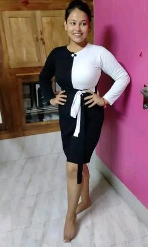 Woman wearing a black and white dress standing against a pink wall.