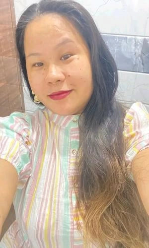 Woman with long dark hair wearing a colorful striped shirt indoors.
