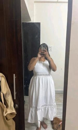Person wearing a white dress standing in front of a mirror.