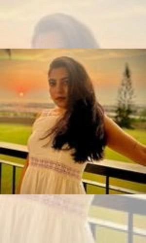 Woman in a white dress standing outdoors with a scenic background