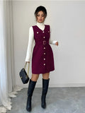 Woman wearing a burgundy dress with white buttons, black knee-high boots, and holding a black handbag.