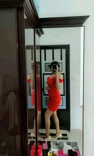 Person wearing a red dress standing in front of a mirror.