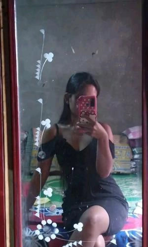 Person taking a mirror selfie wearing a black dress with a colorful background.