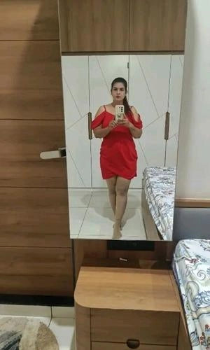 Person wearing a red dress standing in front of a mirror in a room.