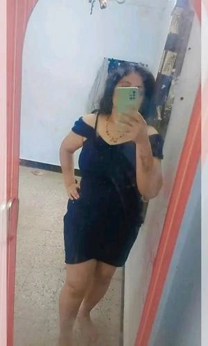 Person wearing a black dress taking a mirror selfie.