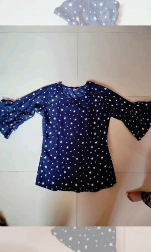 Black top with white star pattern worn by a person on a tiled floor.