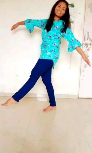 Person wearing a blue floral top and dark blue pants on a light background