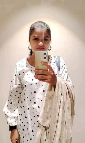 Person taking a mirror selfie wearing a white outfit with star patterns and a beige scarf.