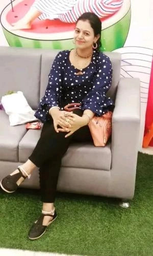 Woman sitting on a gray couch with a colorful background