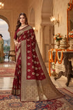 Woman in a red and beige saree standing in an ornate room with decorative elements.