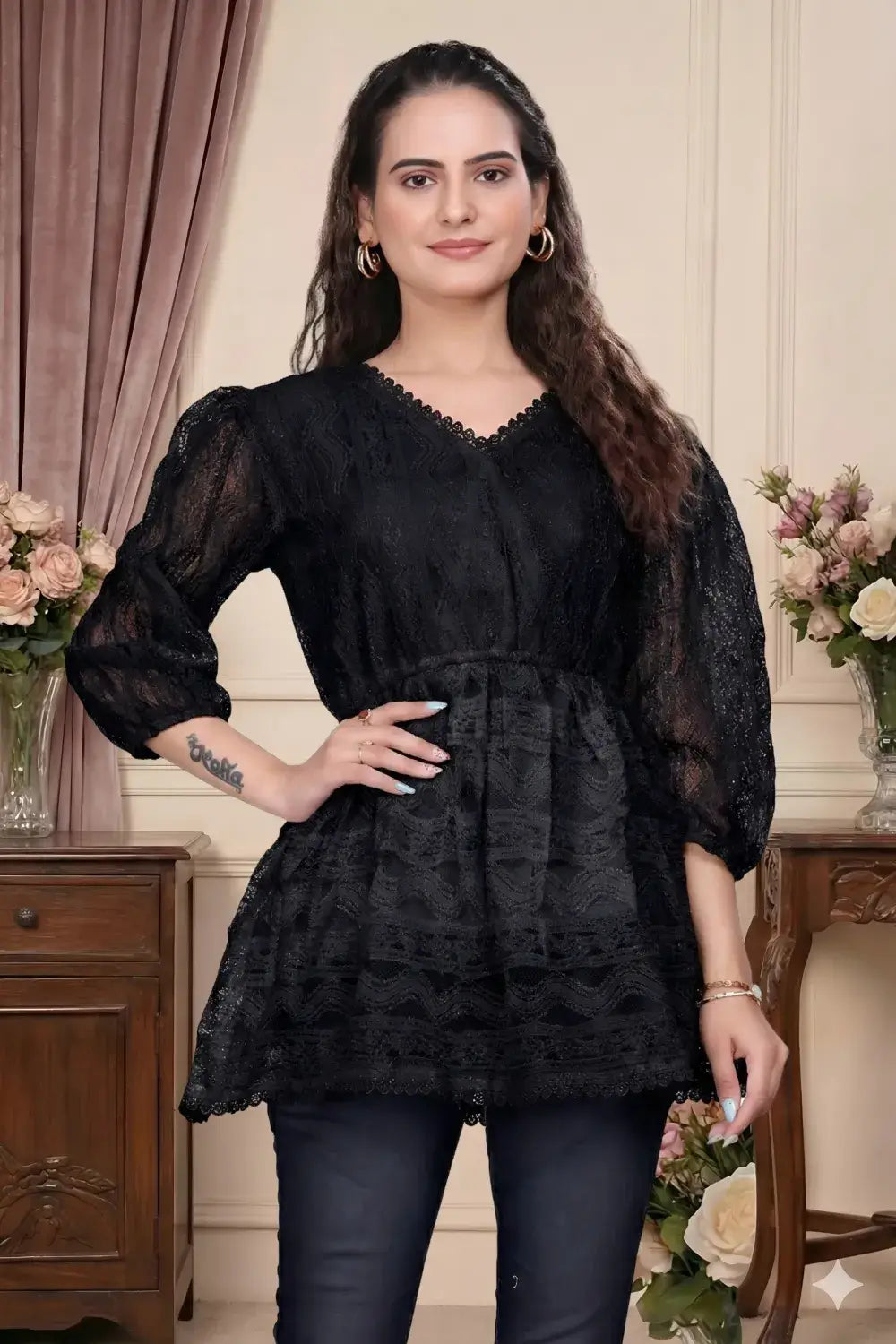 Woman wearing a black lace top with floral decorations in a decorated room.