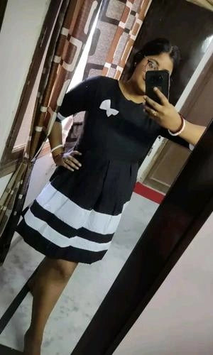 Person wearing a black and white dress taking a mirror selfie.