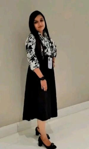 Woman wearing a black and white patterned blouse with a black skirt against a plain background