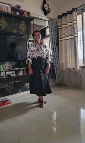 Woman standing in a living room with a television and decorative items.