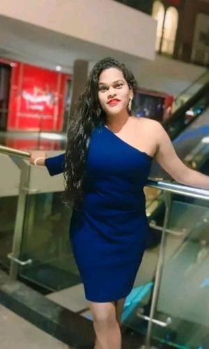 Woman in a blue dress standing on an escalator with a blurred background