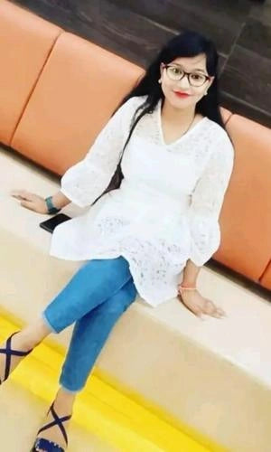 Woman in a white top and blue pants sitting on an orange couch.