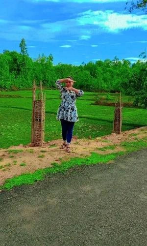 Person standing on a path with greenery and a blue sky in the background