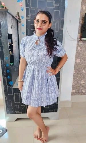 Woman wearing a blue floral dress standing in front of a mirror.
