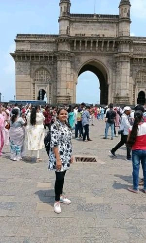 Woman standing in front of the Gateway of India with people around
