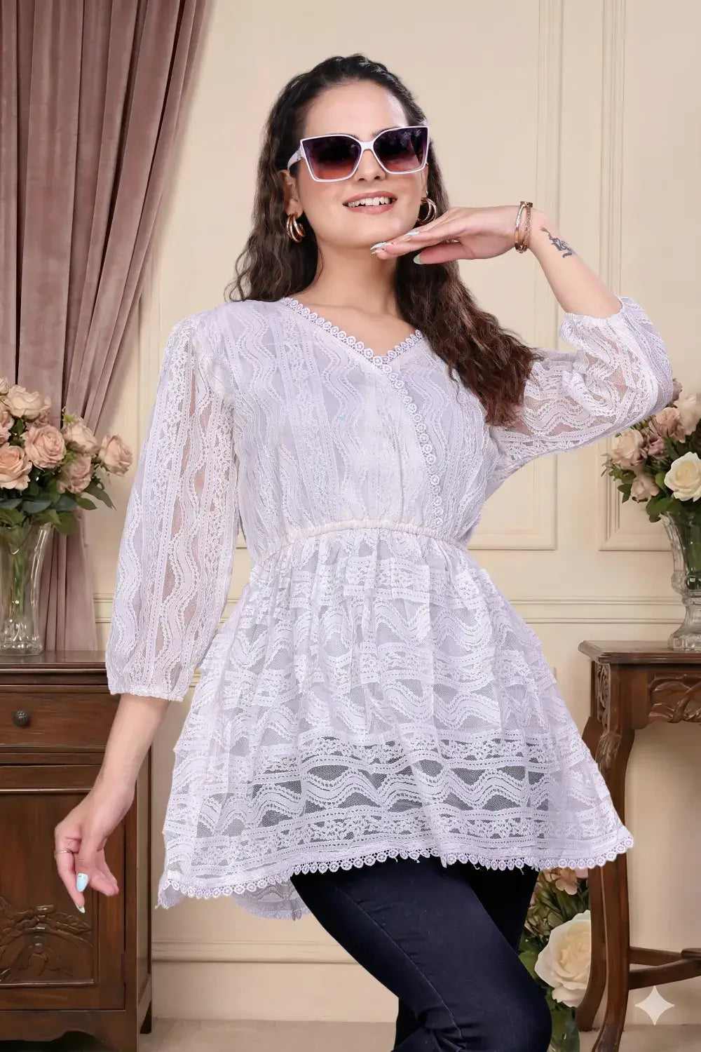 Woman wearing a white lace dress with sunglasses indoors.