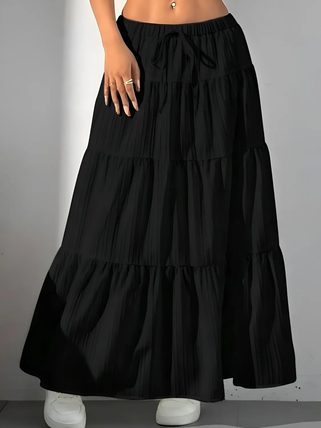 Black tiered skirt worn by a person on a gray background