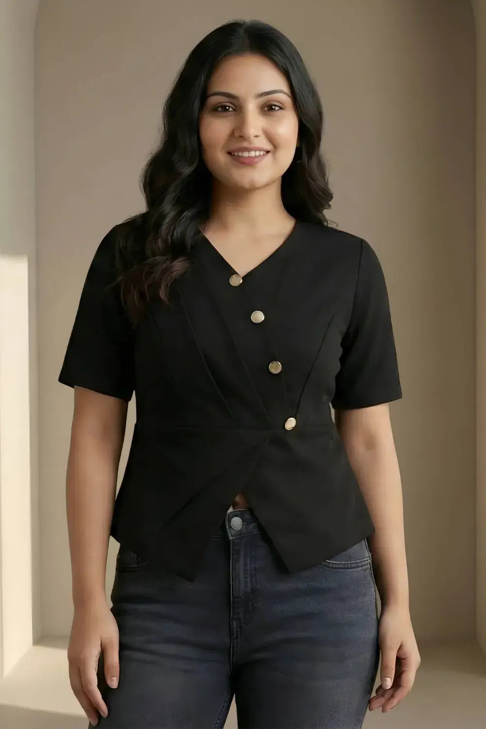 Woman wearing a black top with gold buttons against a beige wall