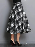 Black and white plaid skirt worn by a person against a gray background