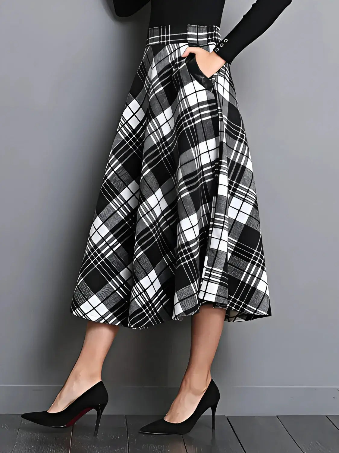 Person wearing a black and white plaid skirt with a plain background