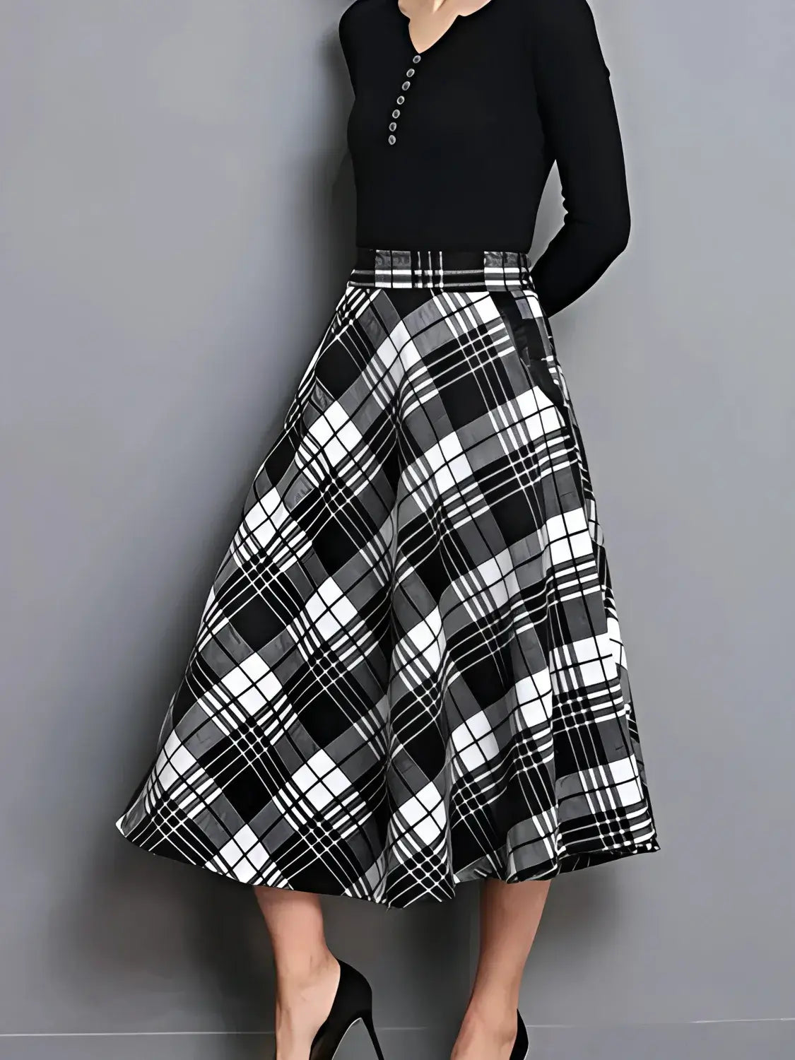 Black and white plaid skirt worn with a black top on a gray background