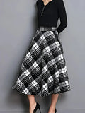 Black and white plaid skirt worn with a black top on a gray background