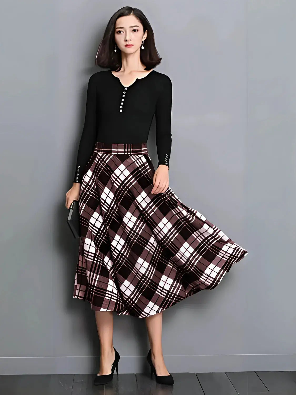 Woman wearing a black top and plaid skirt against a gray background
