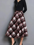 Plaid skirt worn with a black top on a gray background