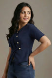 Woman wearing a navy blue top with buttons against a plain background