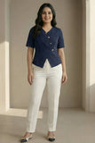 Woman wearing a navy blue top with white pants in a neutral setting