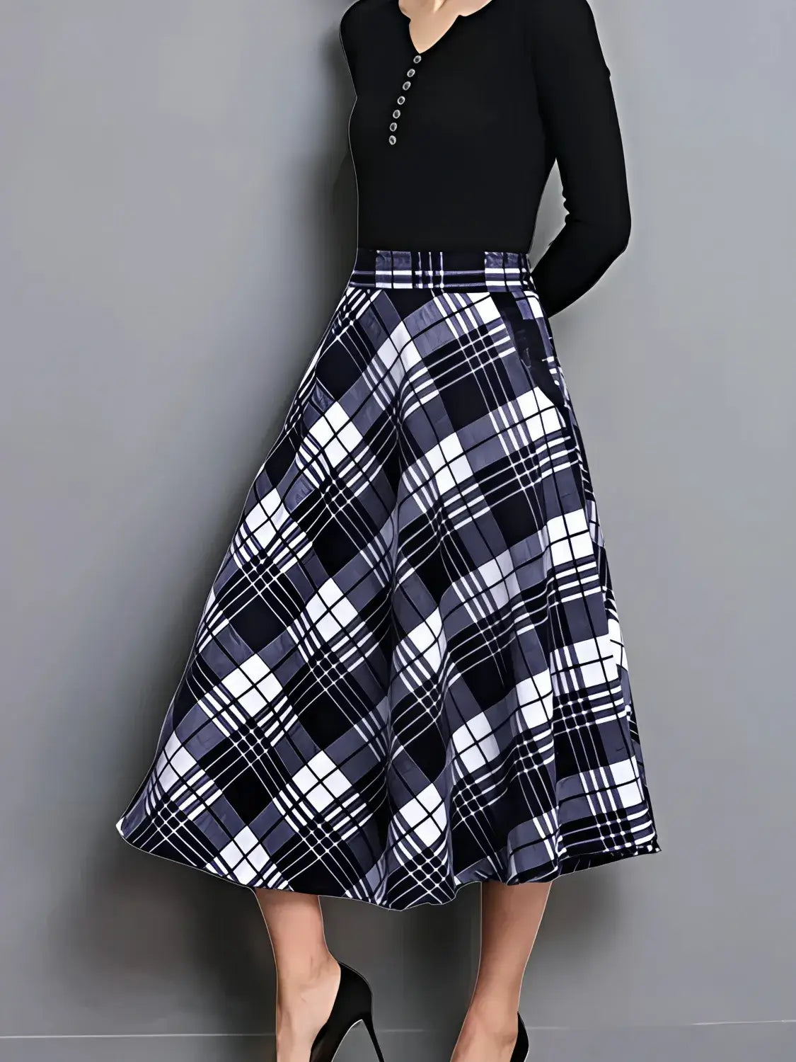 Person wearing a black top and plaid skirt on a gray background