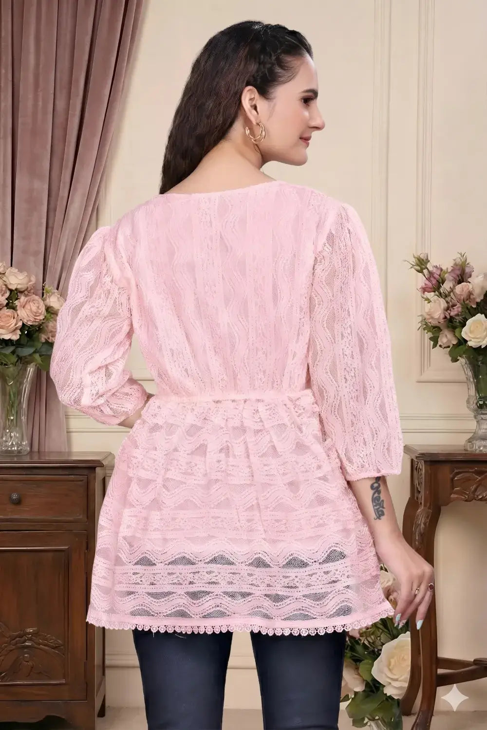 Woman wearing a pink lace dress in an elegant indoor setting.