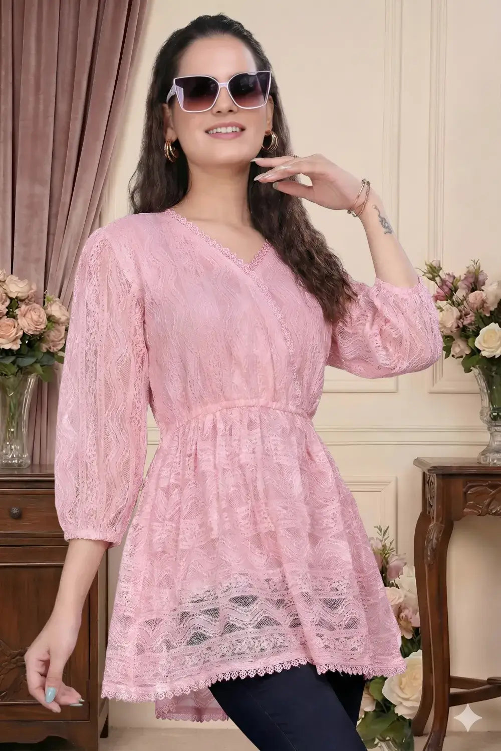 Woman wearing a pink lace dress with sunglasses indoors.