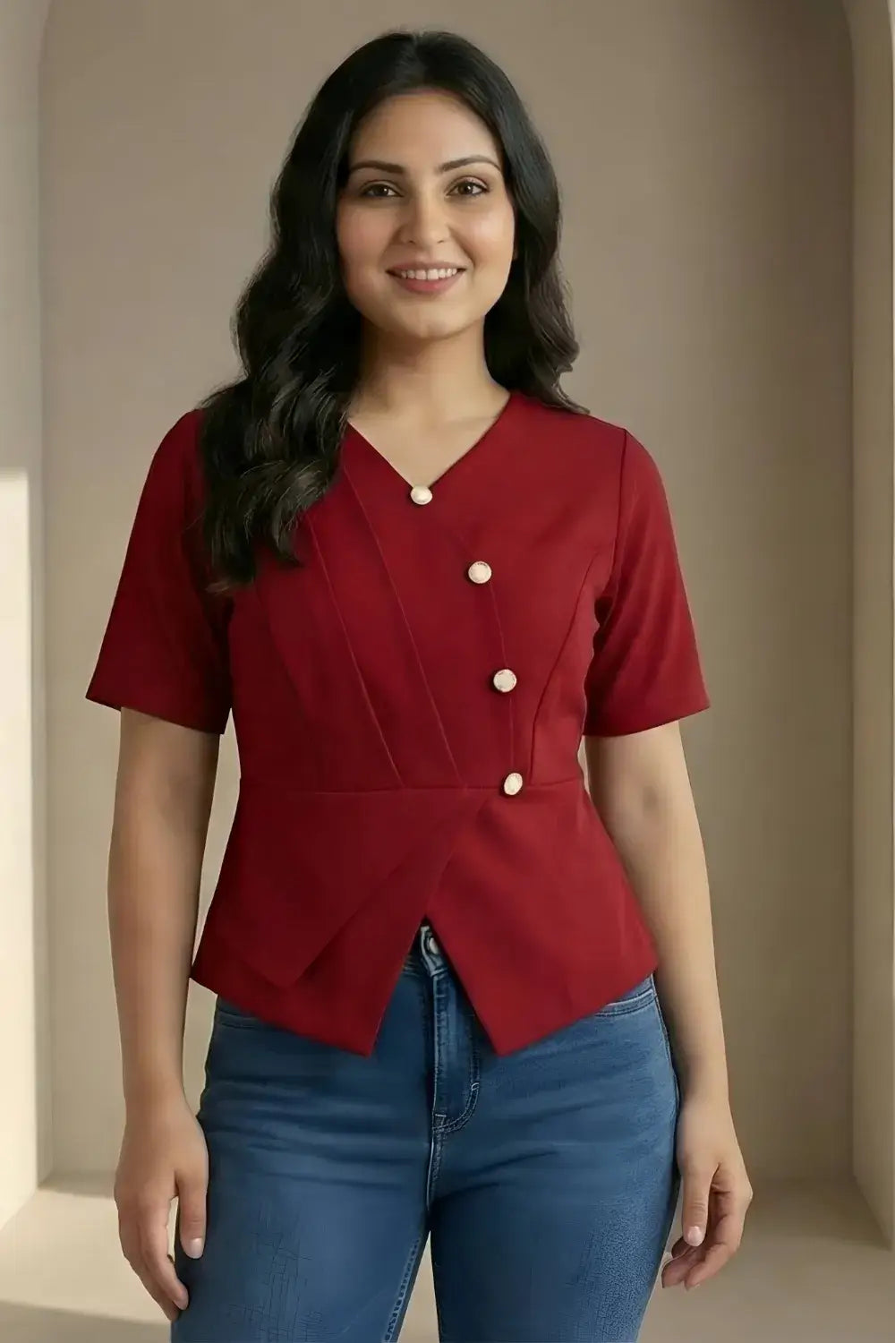 Woman wearing a red blouse with white buttons and blue jeans against a beige background