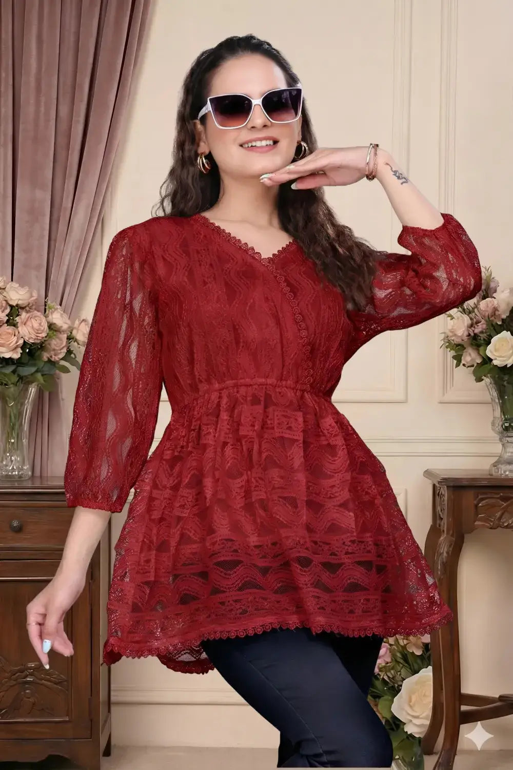 Woman wearing a red lace dress posing indoors with flowers and furniture in the background